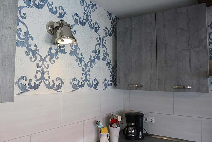 In blau-weiß gehaltene Küche, blaue Ornamente an der Wand