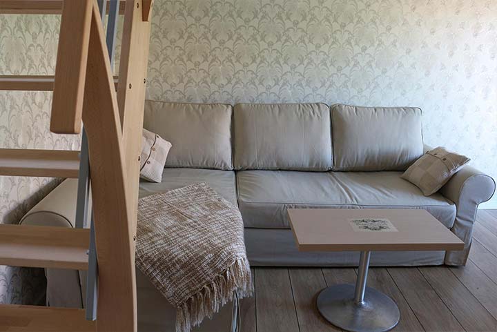 Wohnzimmer tapeziert mit hellerStrukturtapete und warmer Beleuchtung, Treppe nach oben