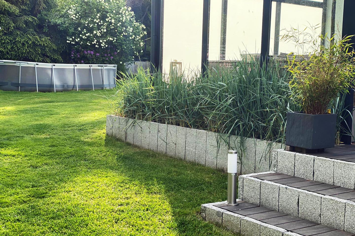 gepflegter Rasen mit Treppe zu einer Veranda